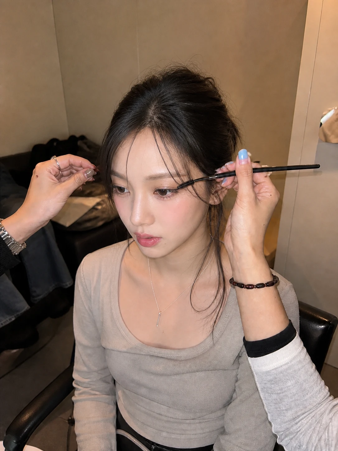 Fictional adult K-pop concept model receiving final eye makeup backstage